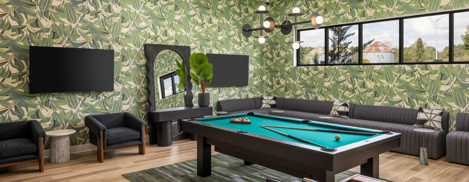 a room with a pool table and chairs and green wallpaper